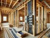 residential-wiring-installation-home-framing High-resolution photograph of an unfinished home under construction, featuring exposed electrical wiring, wooden framing, and scattered building materials in a well-lit, sharp, and detailed setting.